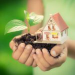 Image of hands cradling tiny house and plant